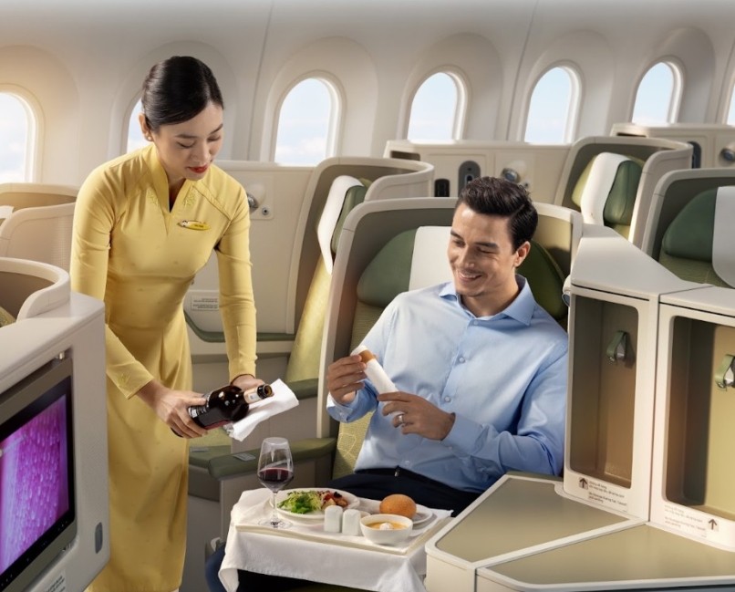 Vietnam Airlines Business Class cabin crew pouring wine for a passenger in a private suite